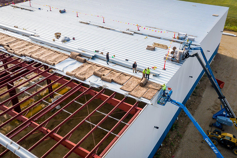 Construction workers installing roof panels on a warehouse